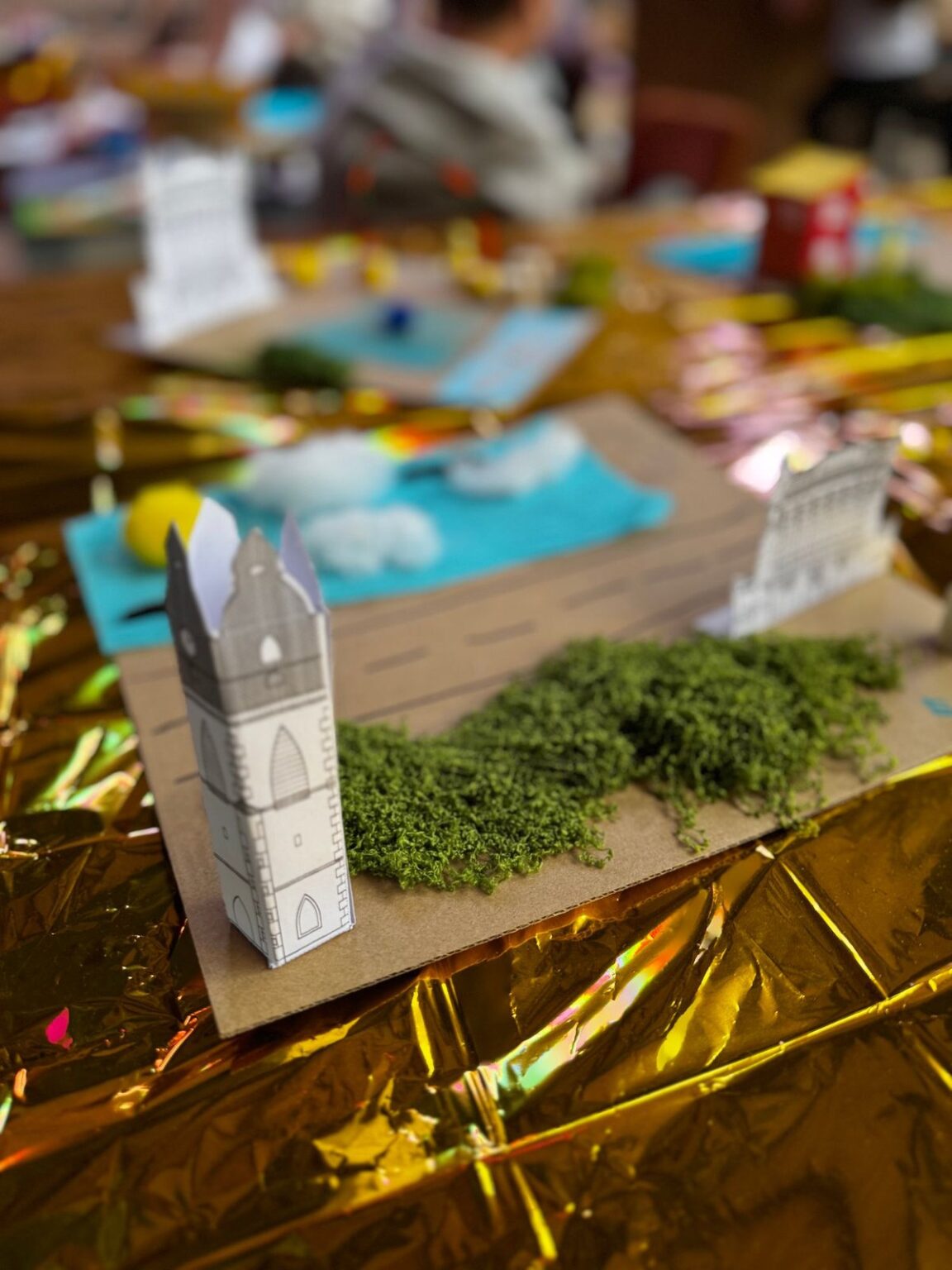 Ein Turm aus Papier zwischen Moos und Goldfolie, gebaut beim Zukunfts-Workshop